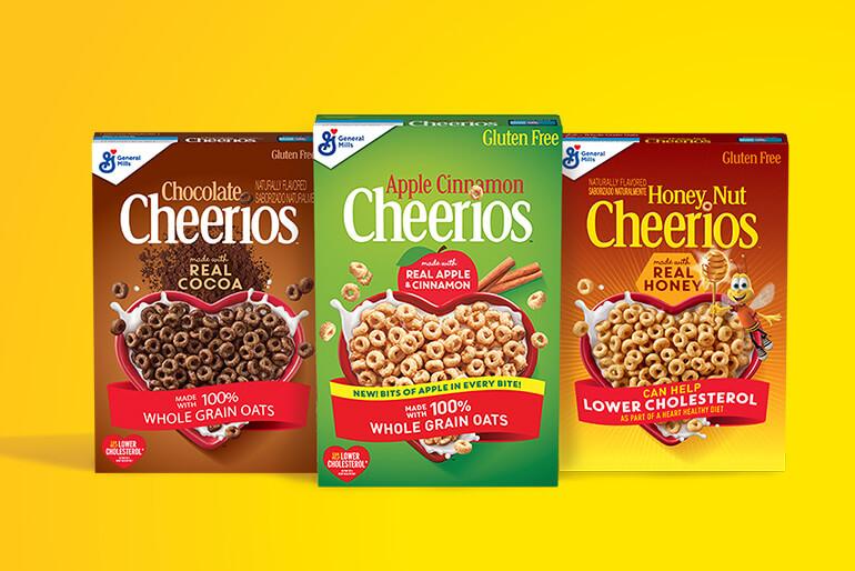 Boxes of Chocolate Cheerios, Apple Cinnamon Cheerios and Honey Nut Cheerios are displayed against a yellow background