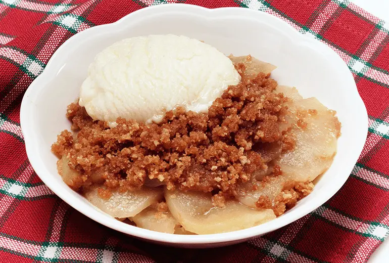 A bowl of baked apple crisp made with Cheerios and topped with a scoop of vanilla ice cream.
