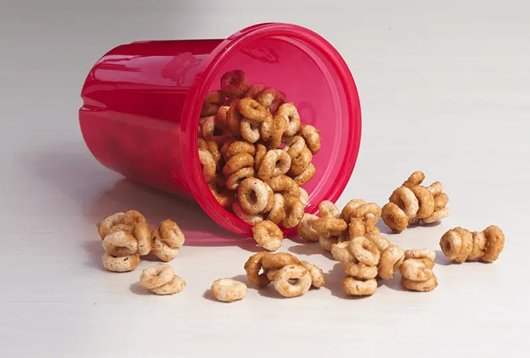 Caramel O’s made with melted butter, brown sugar, salt and Cheerios spilling out of a cup.
