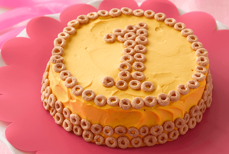 Orange birthday cake made with Betty Crocker yellow cake mix, frosted with cream cheese and Cheerios cereal pieces.