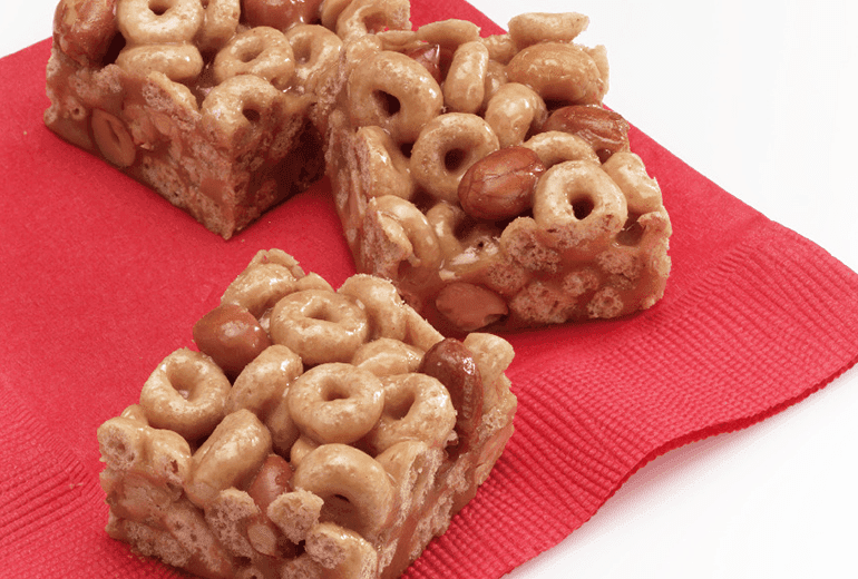 Three squares of Gluten Free Cheerios Honey-Peanut Cereal Bars on a red napkin.