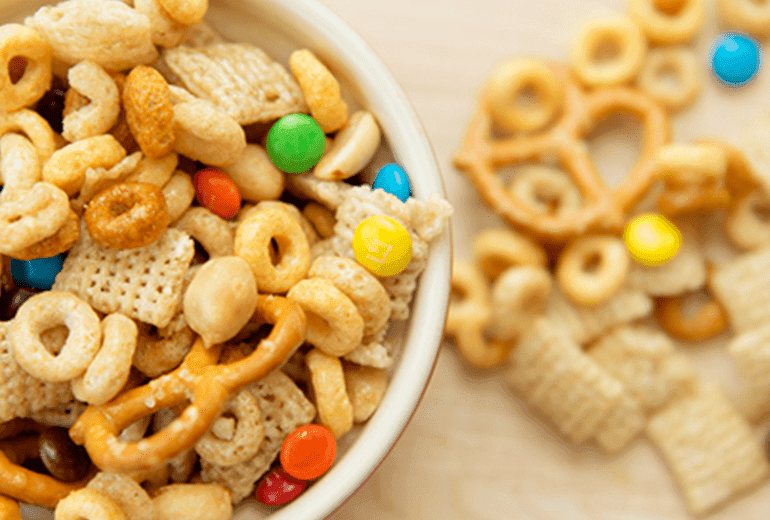 Honey-roasted peanuts, Rice Chex cereal and Multi Grain Cheerios cereal coated in a light honey glaze tossed with candy in a bowl.