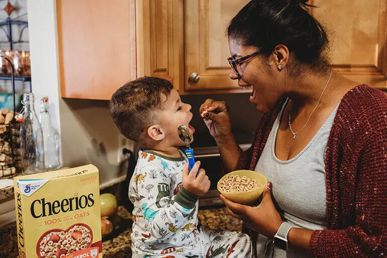 A mother and child enjoying cereal together in a cozy kitchen.