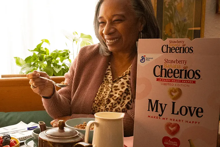 A woman looking happy eating Cheerios cereal