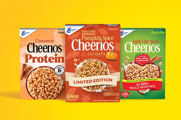 Three boxes of Cheerios cereal are displayed. From left to right: Cinnamon Cheerios Protein with 8g of protein, Pumpkin Spice Cheerios labeled as 'Limited Edition', and Apple Cinnamon Cheerios made with real apple and cinnamon, featuring whole grain oats. All boxes are marked as gluten-free.